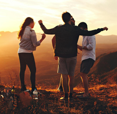 Four Person Standing at Top of Grassy Mountain