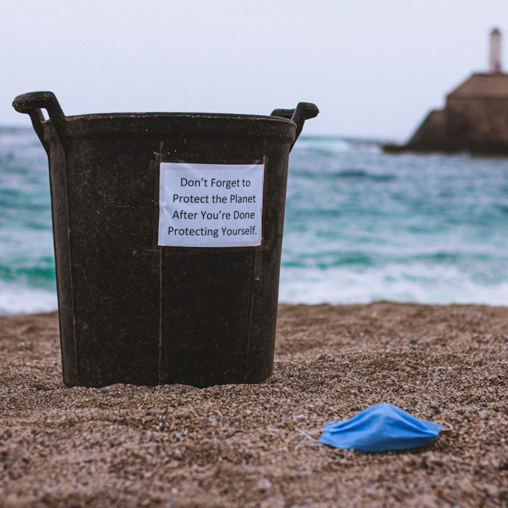 black plastic bucket on brown sand near blue textile during daytime