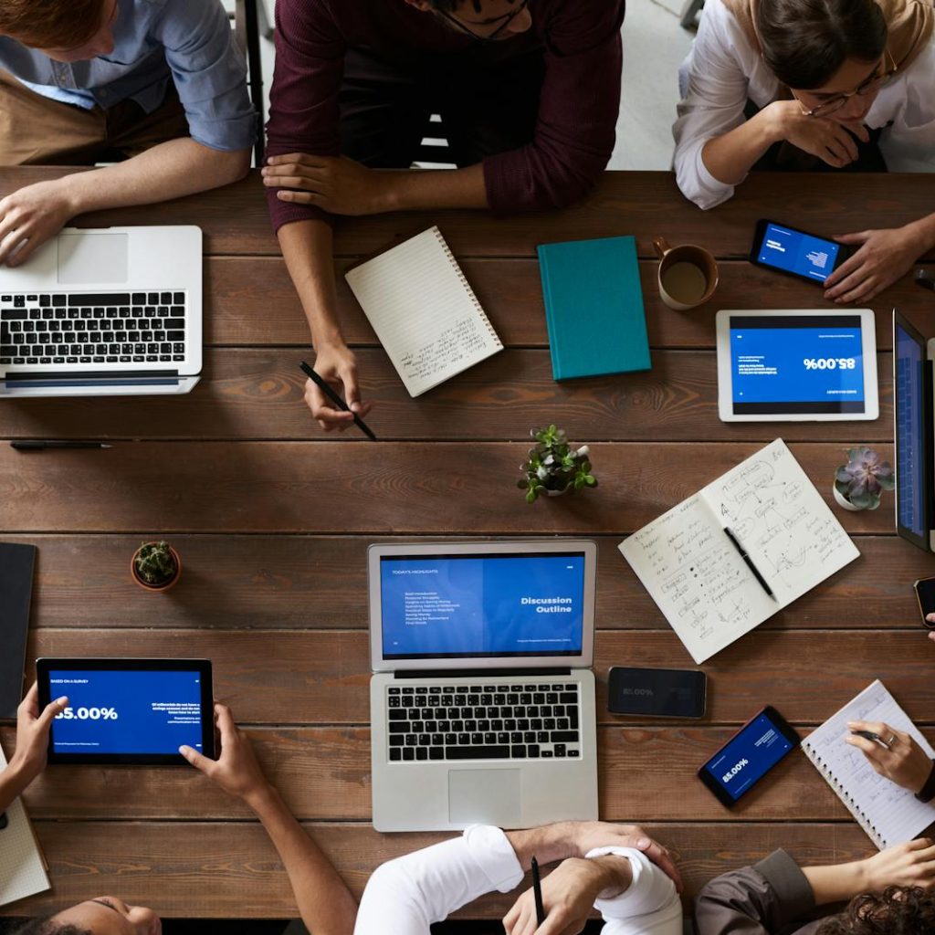 Overhead view of a diverse team in a business meeting using laptops and tablets.