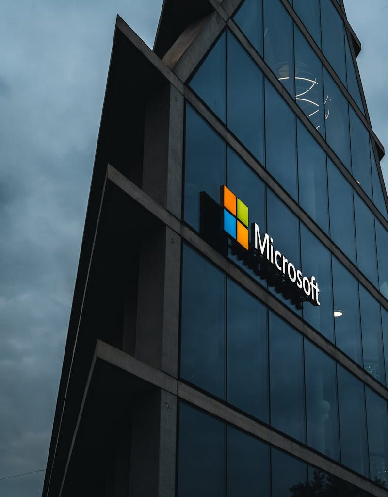 A modern Microsoft office skyscraper with glass facade against a cloudy evening sky.