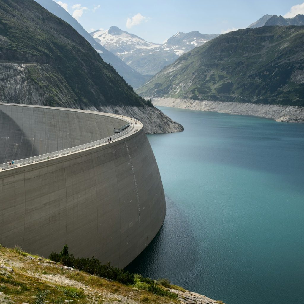 photo of concrete dam in lake near mountains during daytime