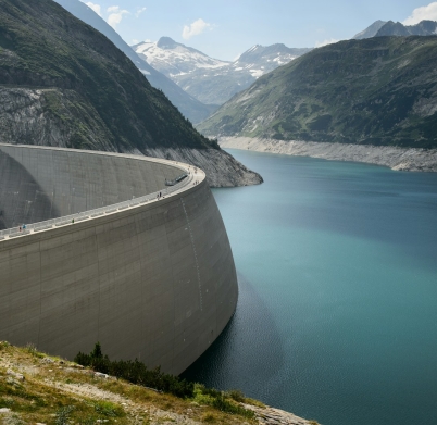 photo of concrete dam in lake near mountains during daytime