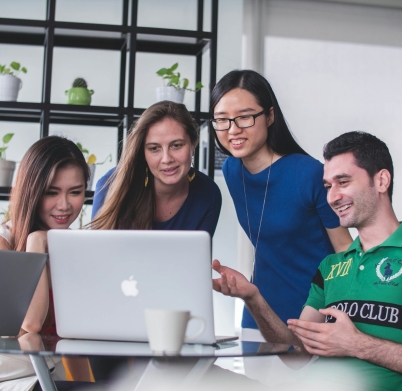 four people watching on white MacBook on top of glass-top table